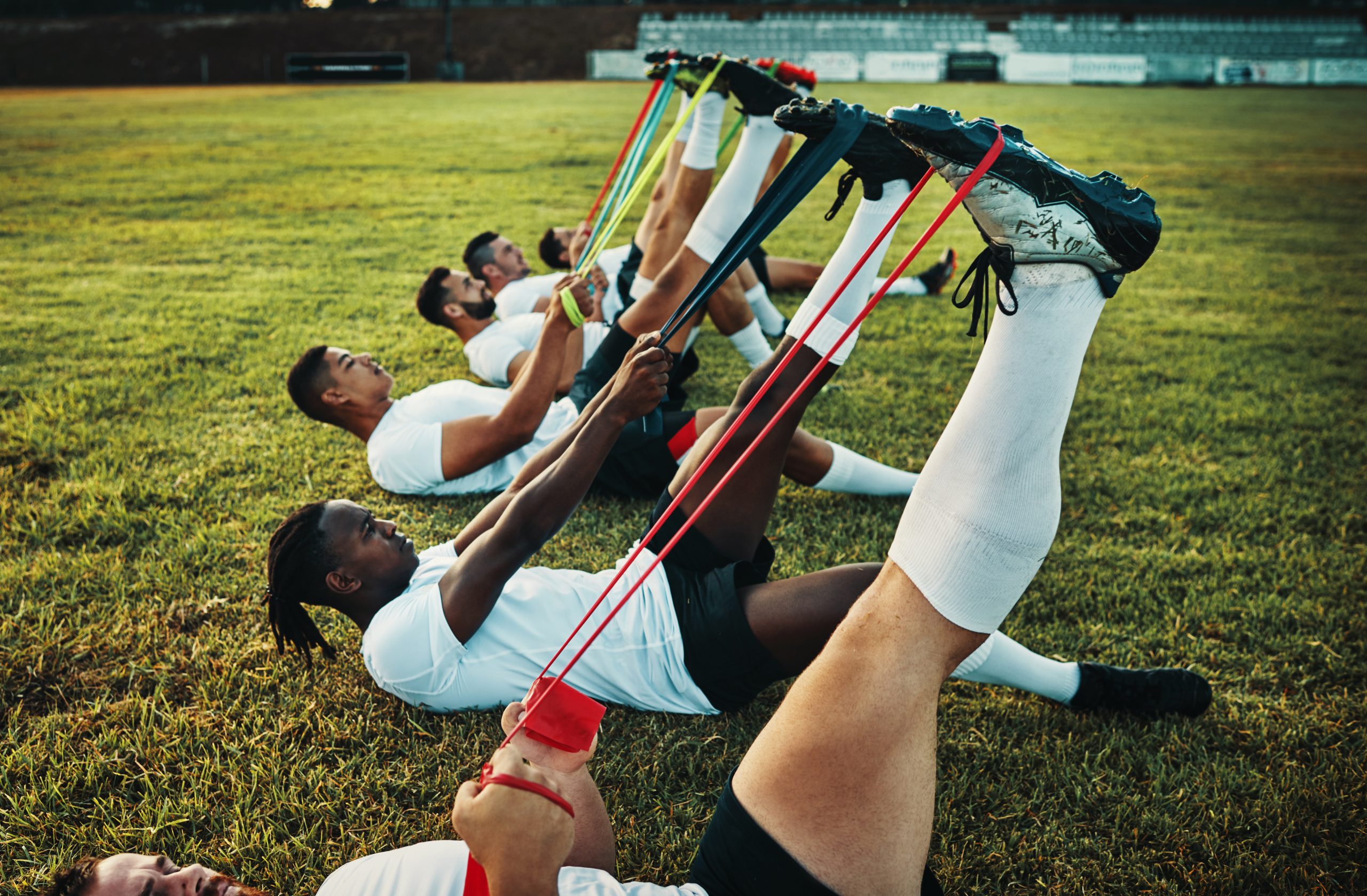 Cropped shot of a group of young rugby players training with bands on the field during the day.