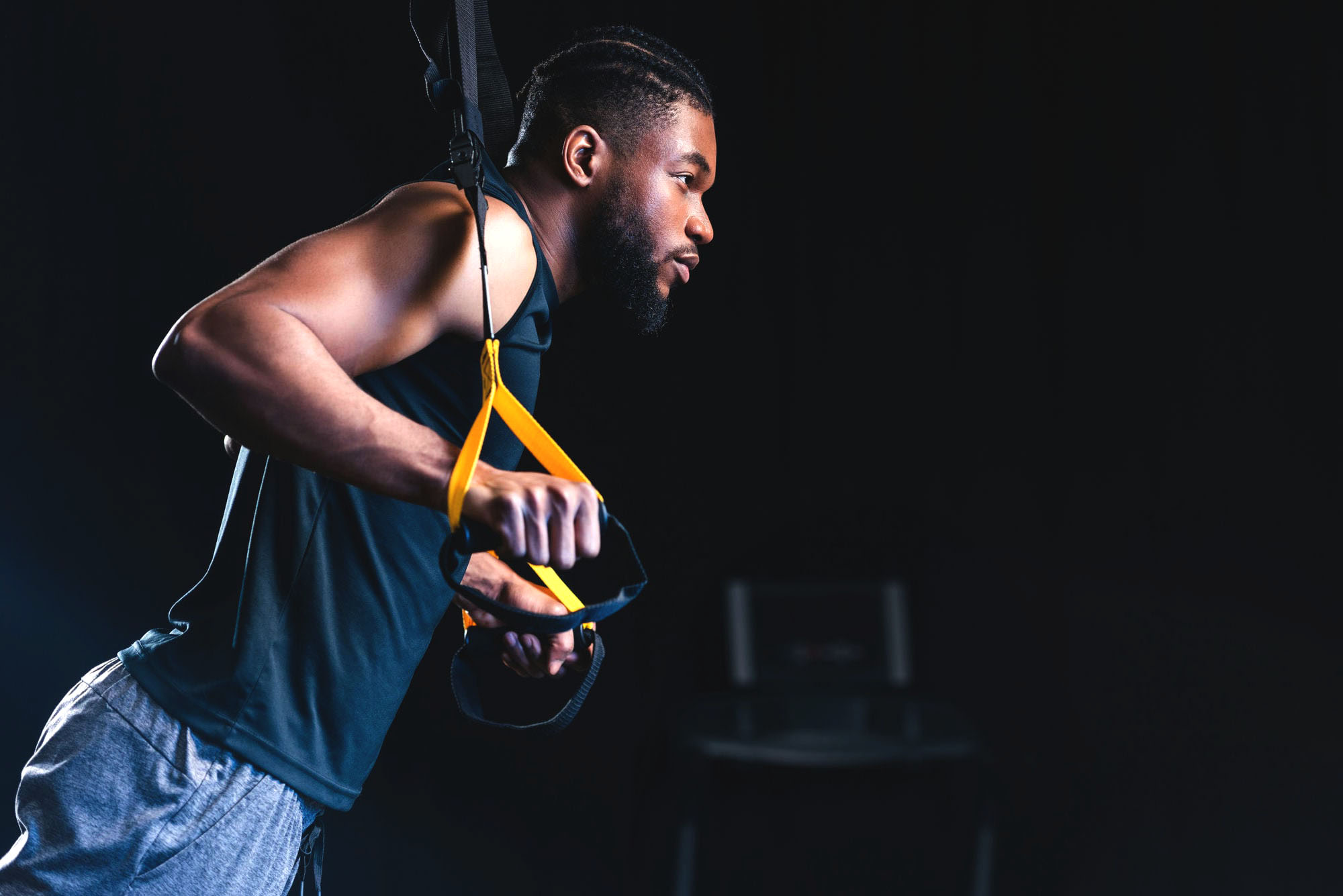 side view of muscular african american man exercising with resistance bands and looking away