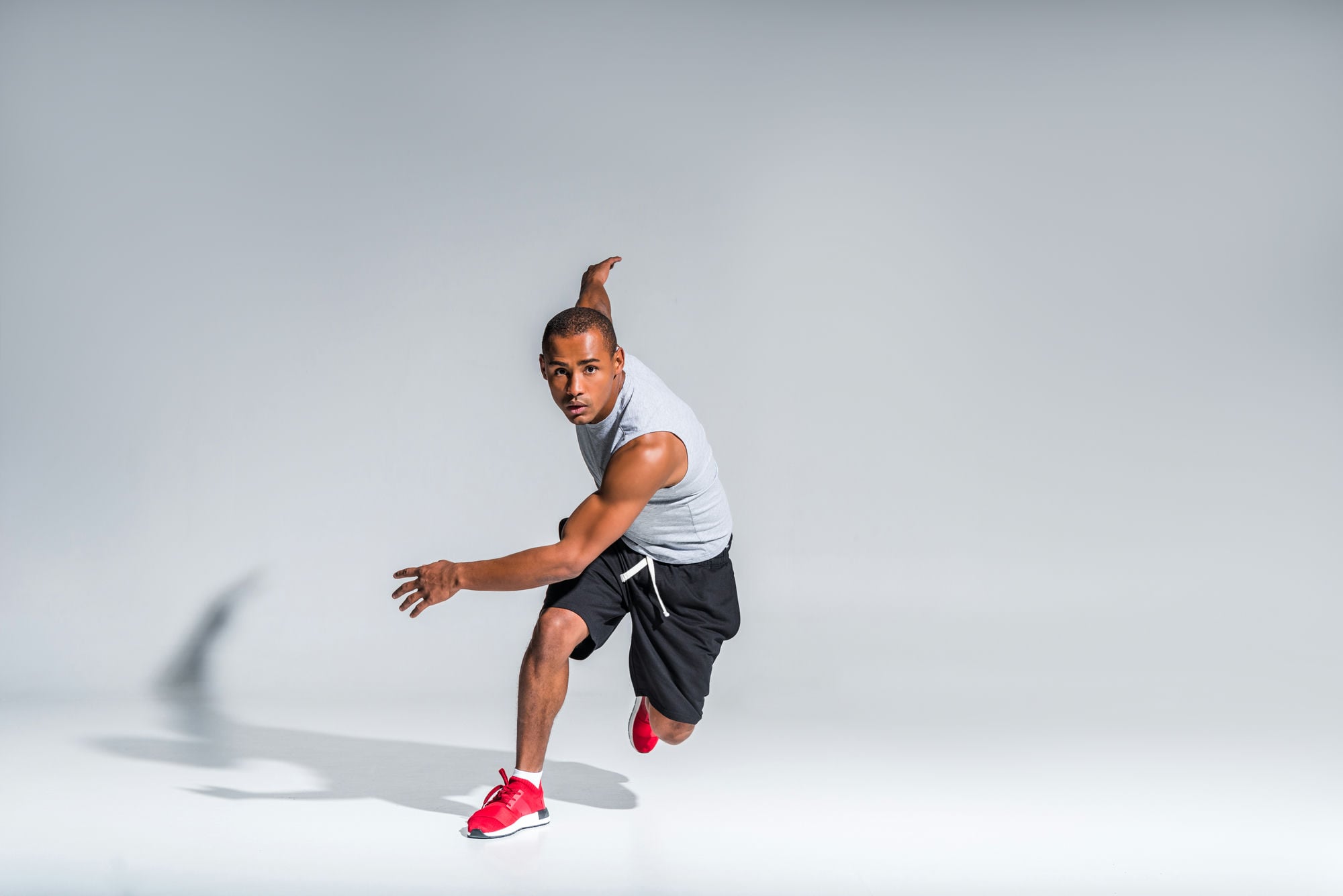 young african american sportsman running and looking at camera on grey